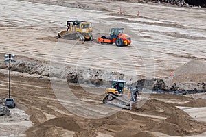 Yellow and black bulldozer pushing sand