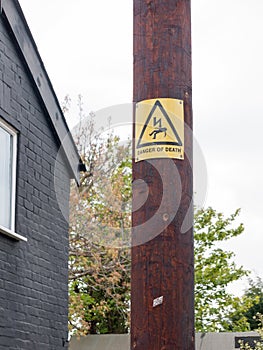 A yellow and black danger of death sign with electric bolt and m