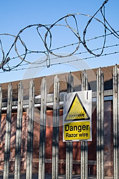 Yellow and Black Danger Razor Wire sign on a metal fence fence