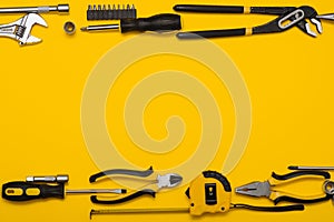 Yellow and black handy tools (pilers and screwdriver) isolated on yellow background.