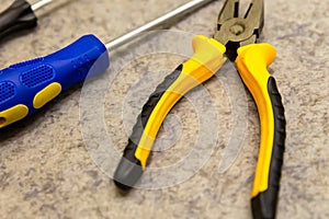 Yellow black pliers close-up screwdriver background base design repair fasteners