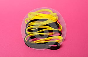 Yellow and black shoe laces on pink background