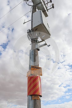 Yellow/black and yellow/red caution and hazard signs in a power pole warning of live electricity cables underground