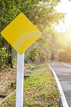 Yellow blank billboard or road sign on the road near green wood