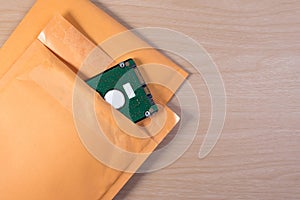 Yellow blank envelope with transparent bubble wrap or packaging shockproof on wooden table with storage hard disk.