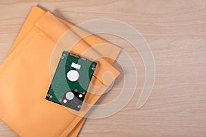 Yellow blank envelope with transparent bubble wrap or packaging shockproof on wooden table with storage hard disk.