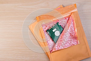 Yellow blank envelope with transparent bubble wrap or packaging shockproof on wooden table with storage hard disk.