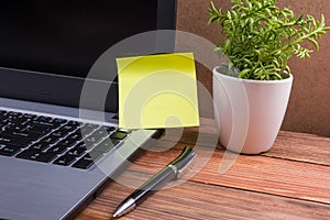 Yellow blank note for ad on computer pc screen, office desk table with suplies wooden grunge vintage background