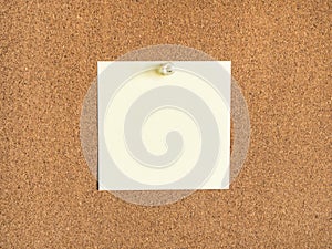 Yellow blank note paper pinned to corkboard