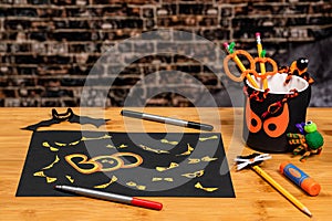 Yellow Bloodshot eyes covering a black sign for Halloween.  Other crafts and supplies scattered on the table. Negative space for