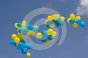 Yellow and blue balloons fly in the bright blue sky on a sunny day