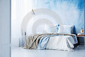 Yellow and blue bedding on white bed in minimal bedroom interior