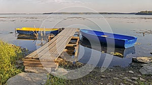 Yellow and blue boat in wooden pier on the lake calm summer evening