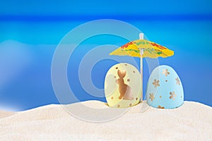 Yellow and blue eggs under umbrella on sandy sea or ocean beach