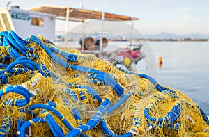 A yellow-and-blue fishing net is piled near a fishing boat