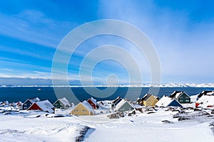 Yellow, blue, red and green inuit houses covered in snow at the