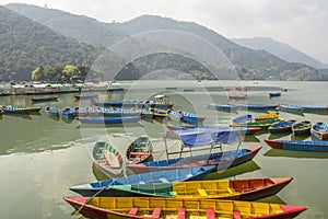 A yellow blue red green wooden boats on a lake against the backdrop of mountains