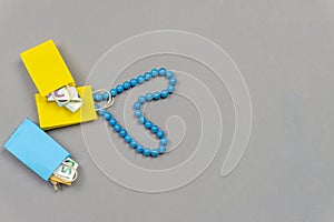 Yellow and blue shopping bags with money and blue necklace on grey background