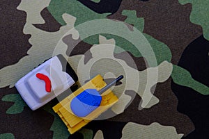 Yellow-blue tanks figures on camouflage background, Ukrainian flag colors on toy tank figures, anti-war concept