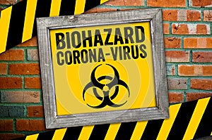 Yellow board in front of a clinker wall with biohazard corona virus