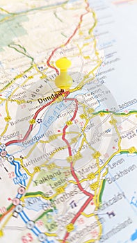 A yellow board pin stuck in Dundee on a map of Scotland portrait photo