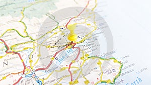 A yellow board pin stuck in Dundee on a map of Scotland photo