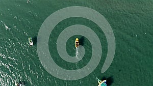 Yellow boat carries an inflatable slide with a roof on the sea for a walk