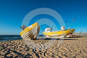 A yellow boat and yellow fishing boat on the beach