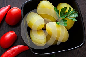 Boiled potatoes with chili peppers and tomatoes on a dark background
