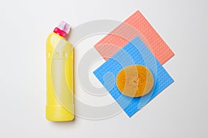 Yellow bottle with cleaning agent, scrubber and dusters on white background  top view