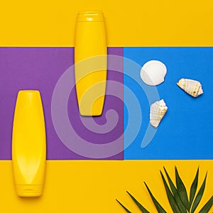 Yellow bottles of sunscreen cream, tropical palm leaves, shells, starfish on colorful background top view flat lay copy space. Sun