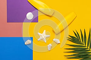 Yellow bottles of sunscreen cream, tropical palm leaves, shells, starfish on colorful background top view flat lay copy space. Sun
