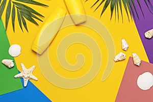 Yellow bottles of sunscreen cream, tropical palm leaves, shells, starfish on colorful background top view flat lay copy space. Sun