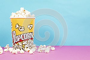Yellow box of fresh popcorns on a pink and blue background