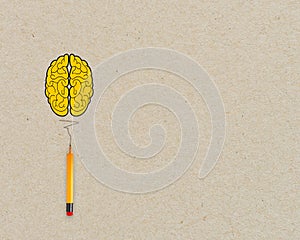 Yellow brain light bulb metaphor for idea with pencil on brown recycled background