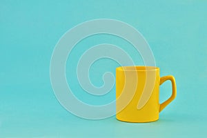 Yellow bright ceramic mug on a light blue background.