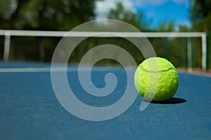 Yellow tennis ball on blue carpet of opened court. photo