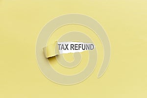 Yellow broken paper background with the word TAX REFUND. Finance