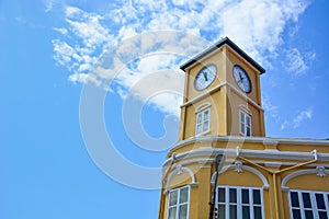 Yellow building with clock tower in Chino-Portuguese style on blue sky background, Phuket old town, Thailand photo