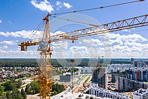 Yellow building cranes on construction site against blue sky background.