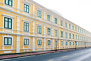 Yellow building with green window in vintage style on day with clear sky