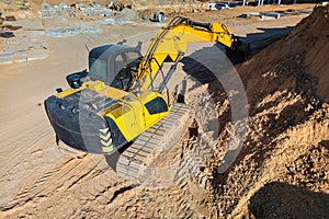 A yellow bulldozer actively excavating soil on a construction site, preparing the ground for future development