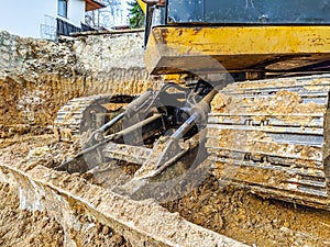 Yellow bulldozer excavator shoveling and digging the ground while working on the difficult excavation, new modern industrial