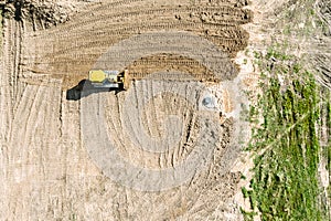 Yellow bulldozer leveling the ground before construction works. aerial view