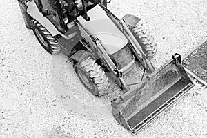 Yellow bulldozer, loading gravel for road construction. Black and white