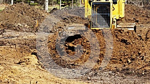 A yellow Bulldozer pushes brown soil toward the camera