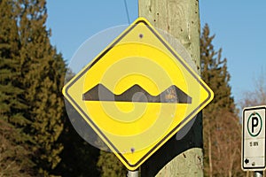 Yellow bumps ahead sign on a wooden pole