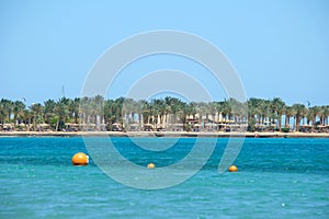 Yellow buoys floating on sea surface as marker for swimming restriction in deep water at tropical resort with view of