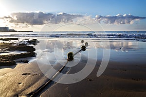 Yellow buoys on rope lying on sandy beach with small waves on sea and beautiful clouds during sunrise, sunny summer morning