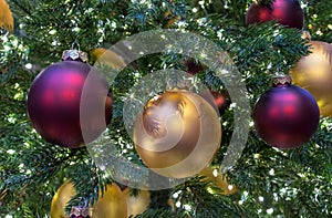 Yellow and burgundy matte Christmas balls on Christmas tree with a garland.